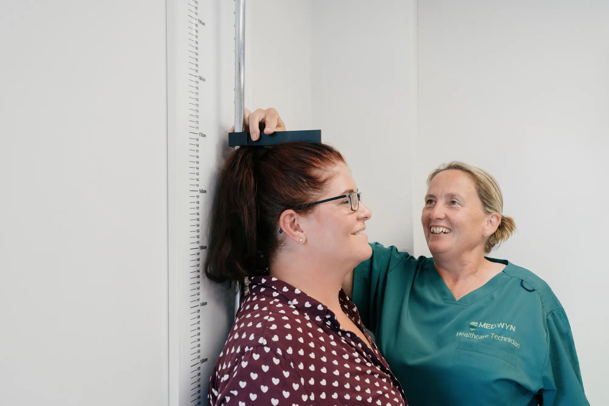 A healthcare technician measuring a patient's height at the Medwyn clinic